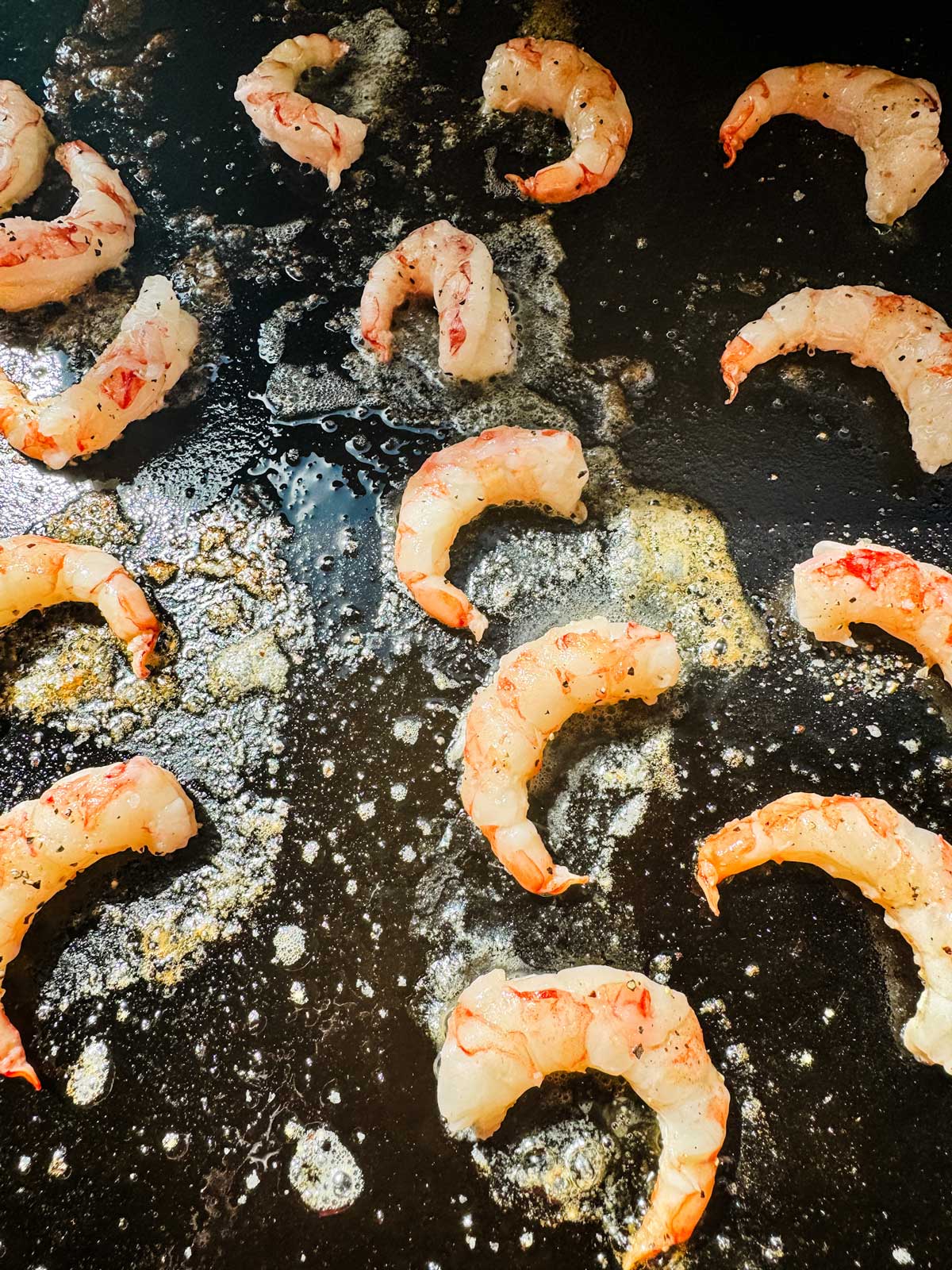 Shrimp that have just been added to a Blackstone griddle.