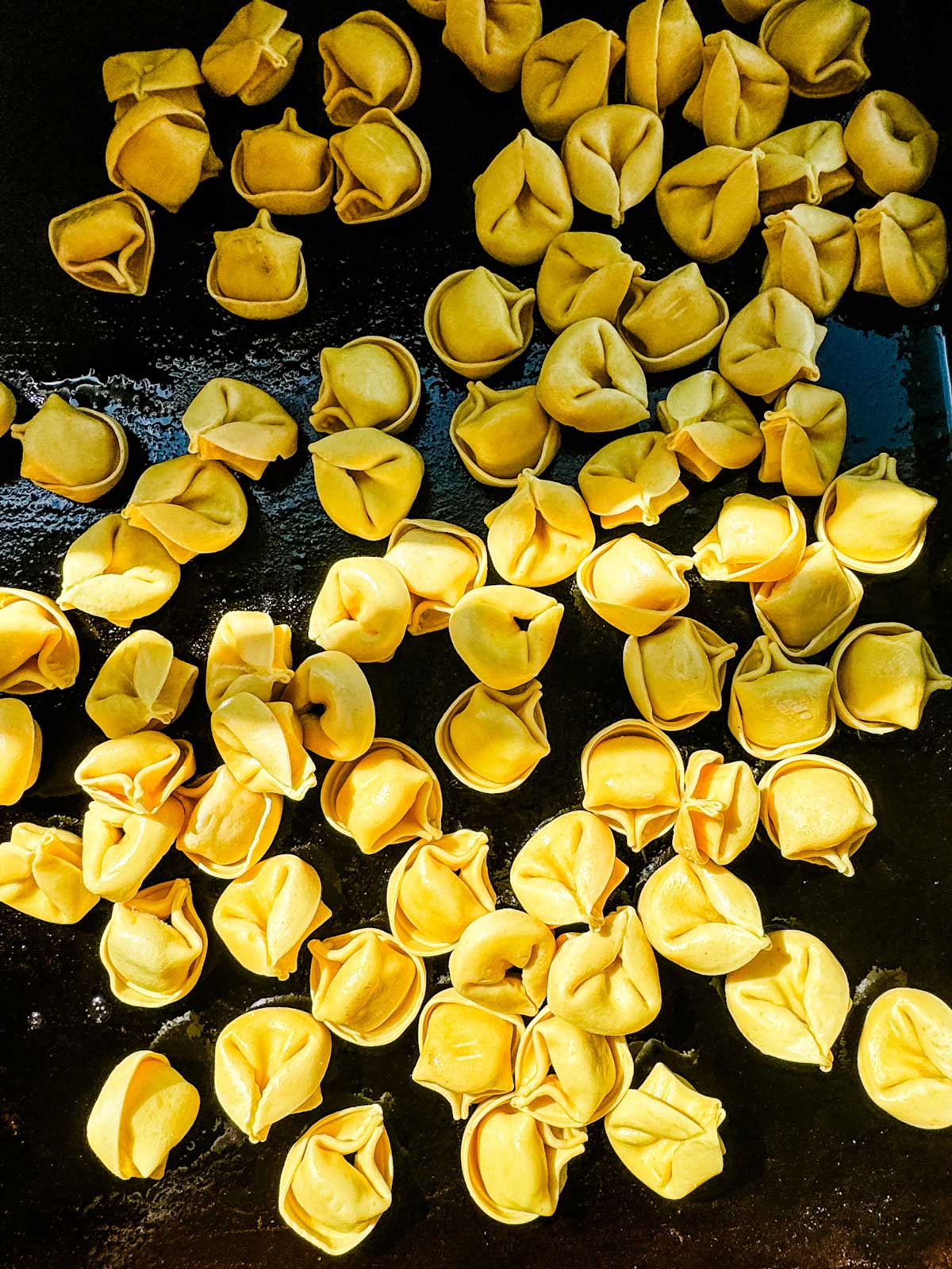 Tortellini that have just been added to a blackstone griddle.