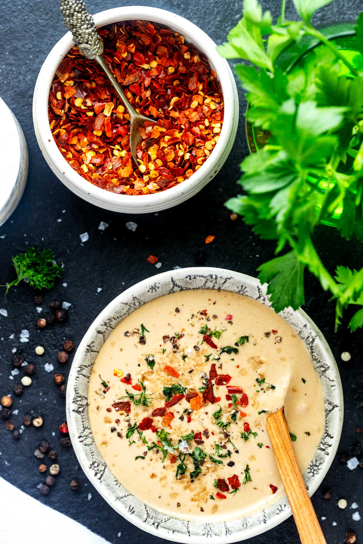 Photo of a small bowl with creamy mustard sauce garnished with parsley and crushed red pepper flakes.