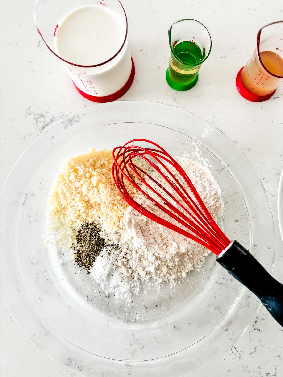 Flour parmesan, and seasonings being whisked together in a pie plate.