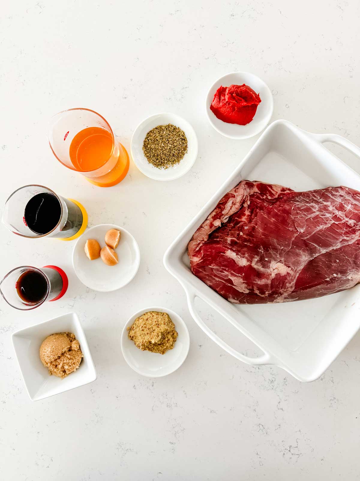 Overhead photo of a flank steak surrounded by ingredients for its marinade.