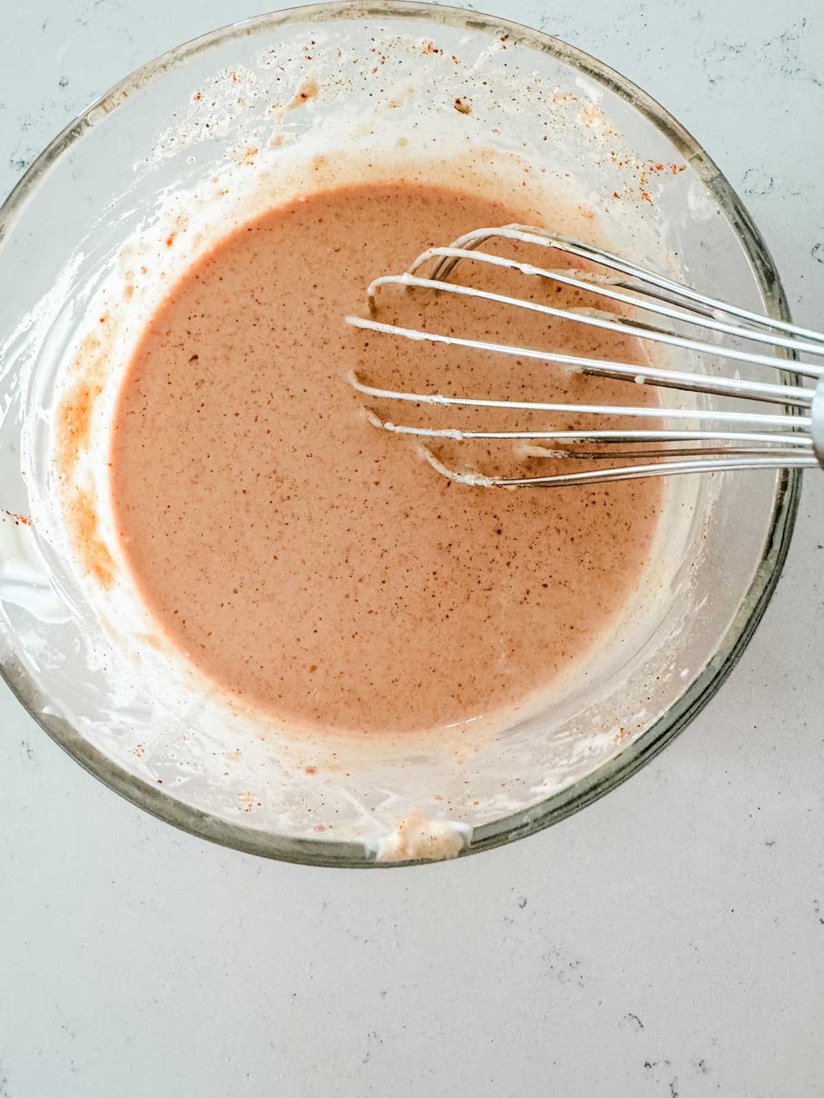 Yum yum sauce in a mixing bowl with a whisk.