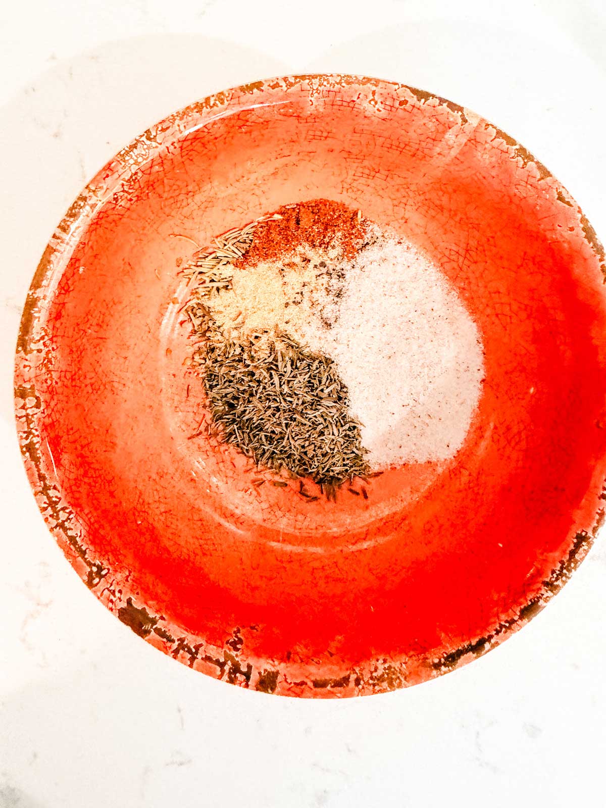 A bright red ceramic bowl containing piles of spices.