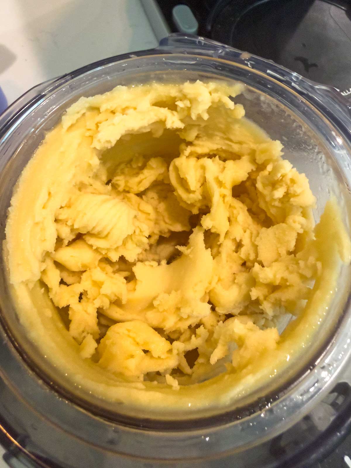 Thick, creamy peach sorbet in a clear mixing bowl, freshly churned and ready to be served. The ice cream has a smooth, slightly textured appearance.