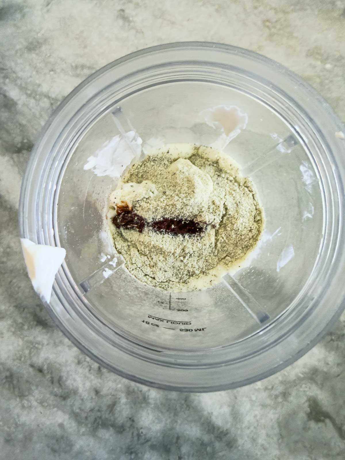 Overhead view of a blender cup containing ingredients for chipotle ranch dressing.