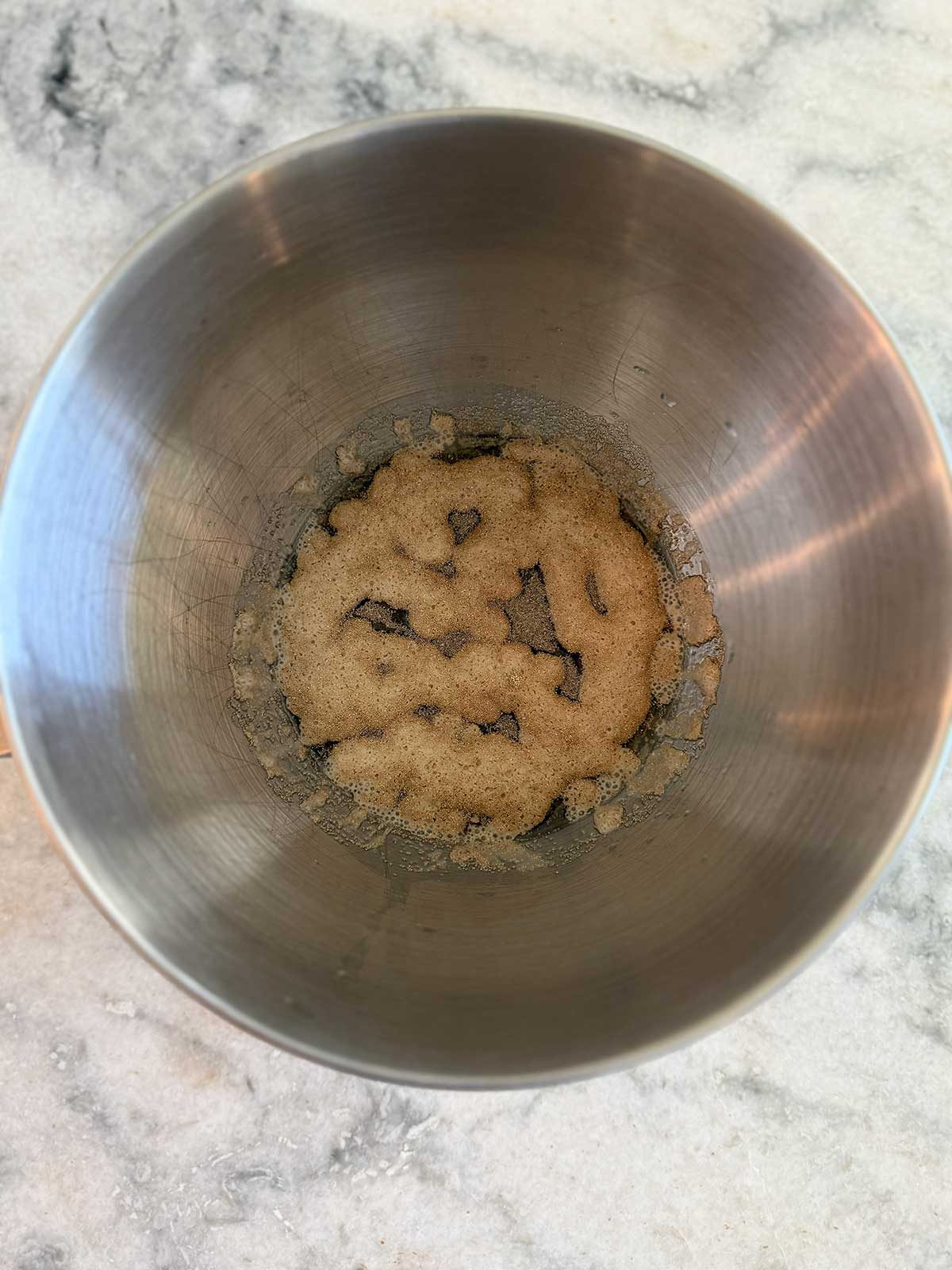 A metal mixing bowl containing yeast proofing.