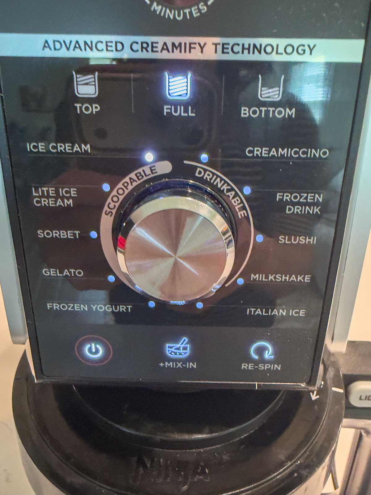 Close-up of a Ninja ice cream maker control panel showing options like ice cream, gelato, sorbet, milkshake, slushi, and mix-in, with a central dial and LED indicators for different settings—perfect for creating seasonal favorites like Ninja Creami Pumpkin Ice Cream.