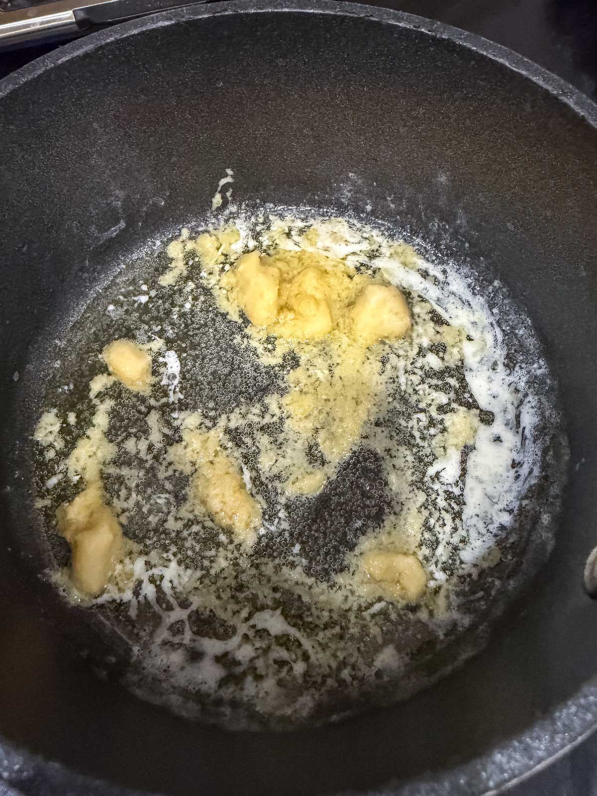 Butter melting and mixing with flour in a dark nonstick pan, forming the early stage of a roux for cooking, as the mixture begins to bubble and dissolve—perfect for preparing sauces to drizzle over Honey Garlic Salmon or crispy Air Fryer Salmon Bites.